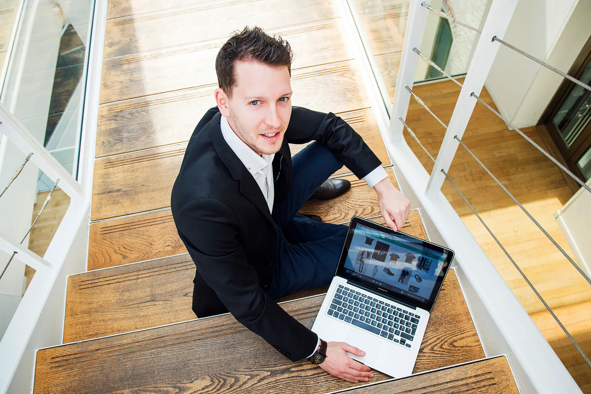 portrait d'un homme et son laptop dans les escaliers