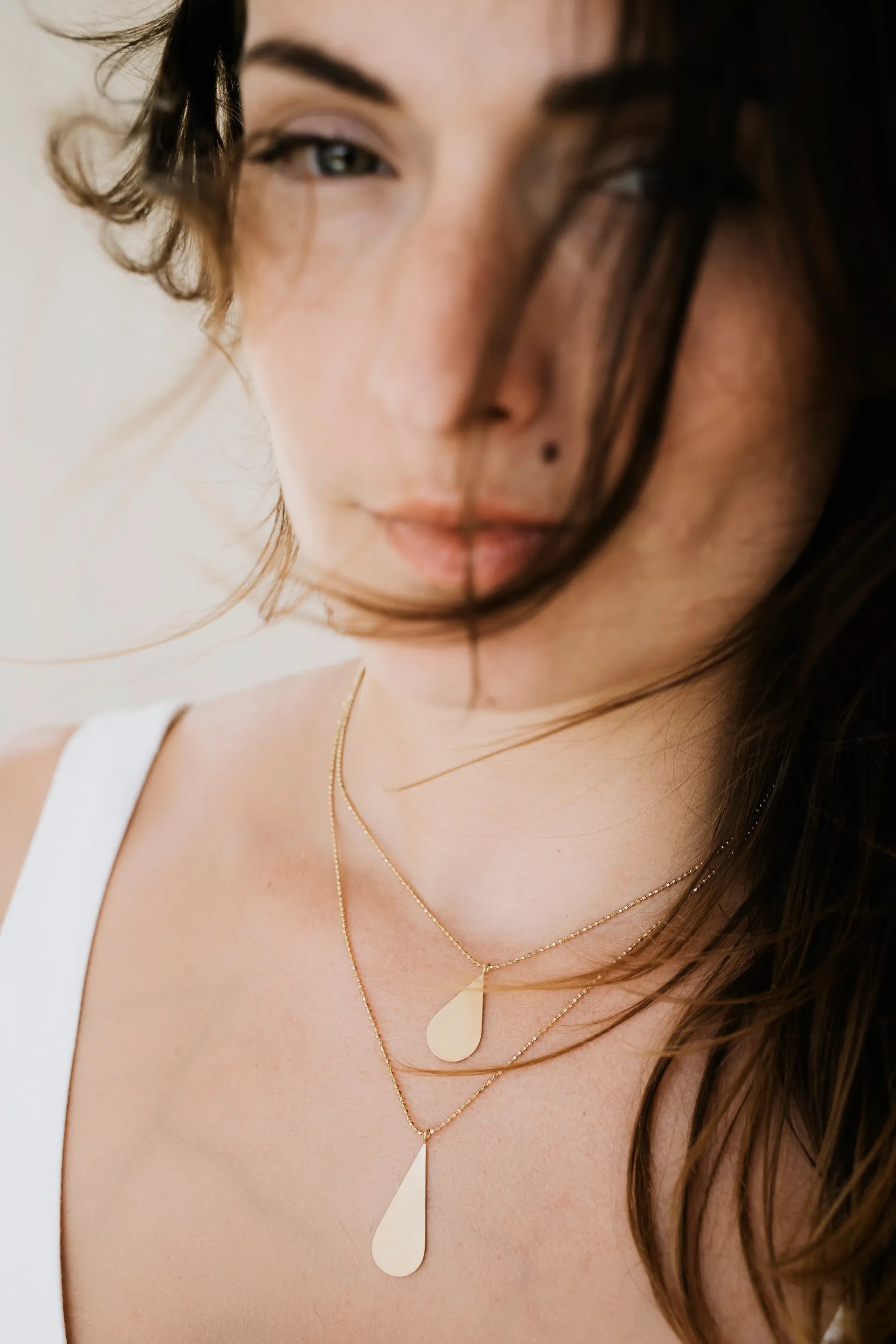 portrait d'une femme en robe blanche portant un collier en or