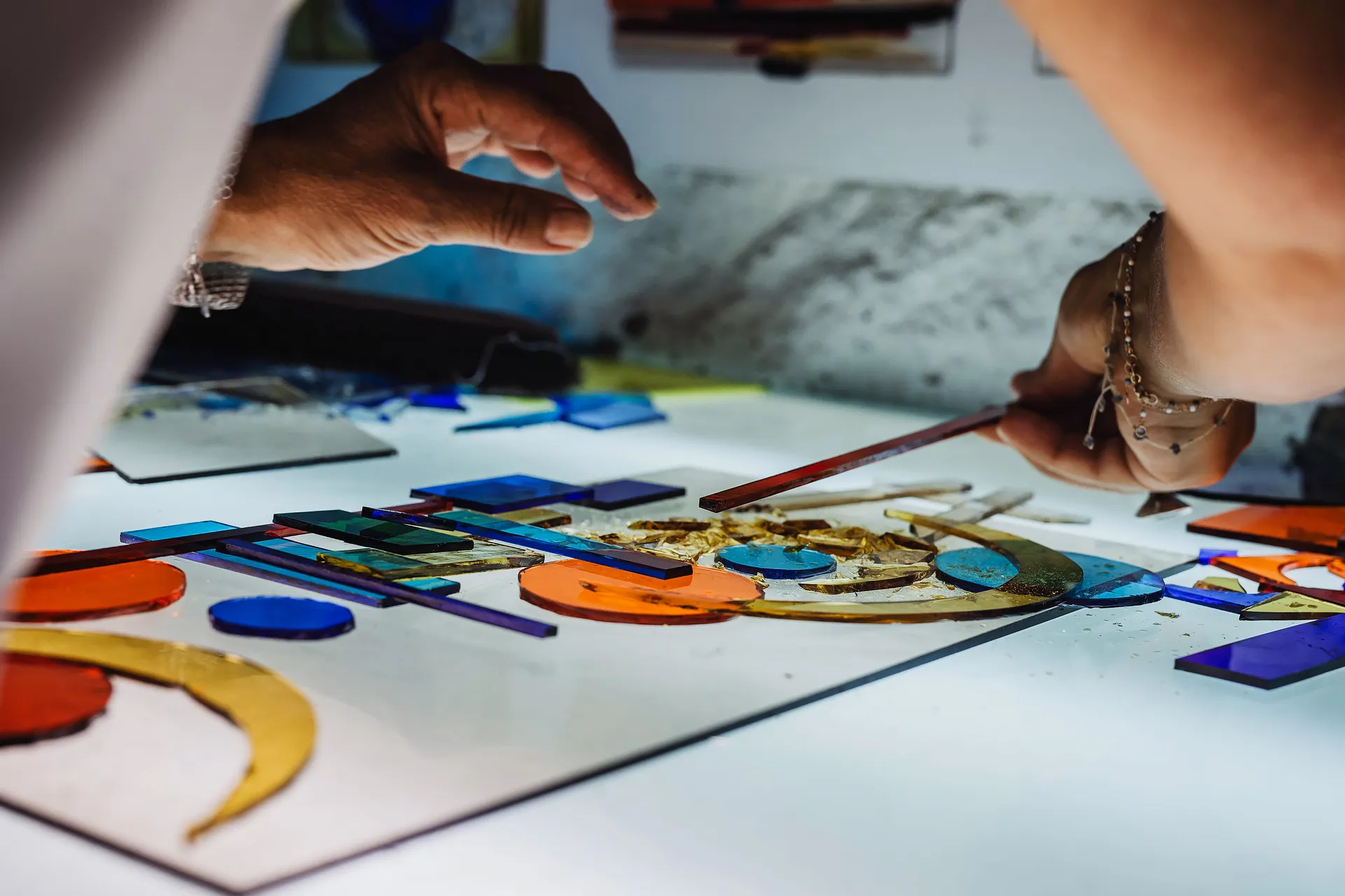 travail en cours, du verre de couleur découpé en formes géométriques est disposé sur une table lumineuse