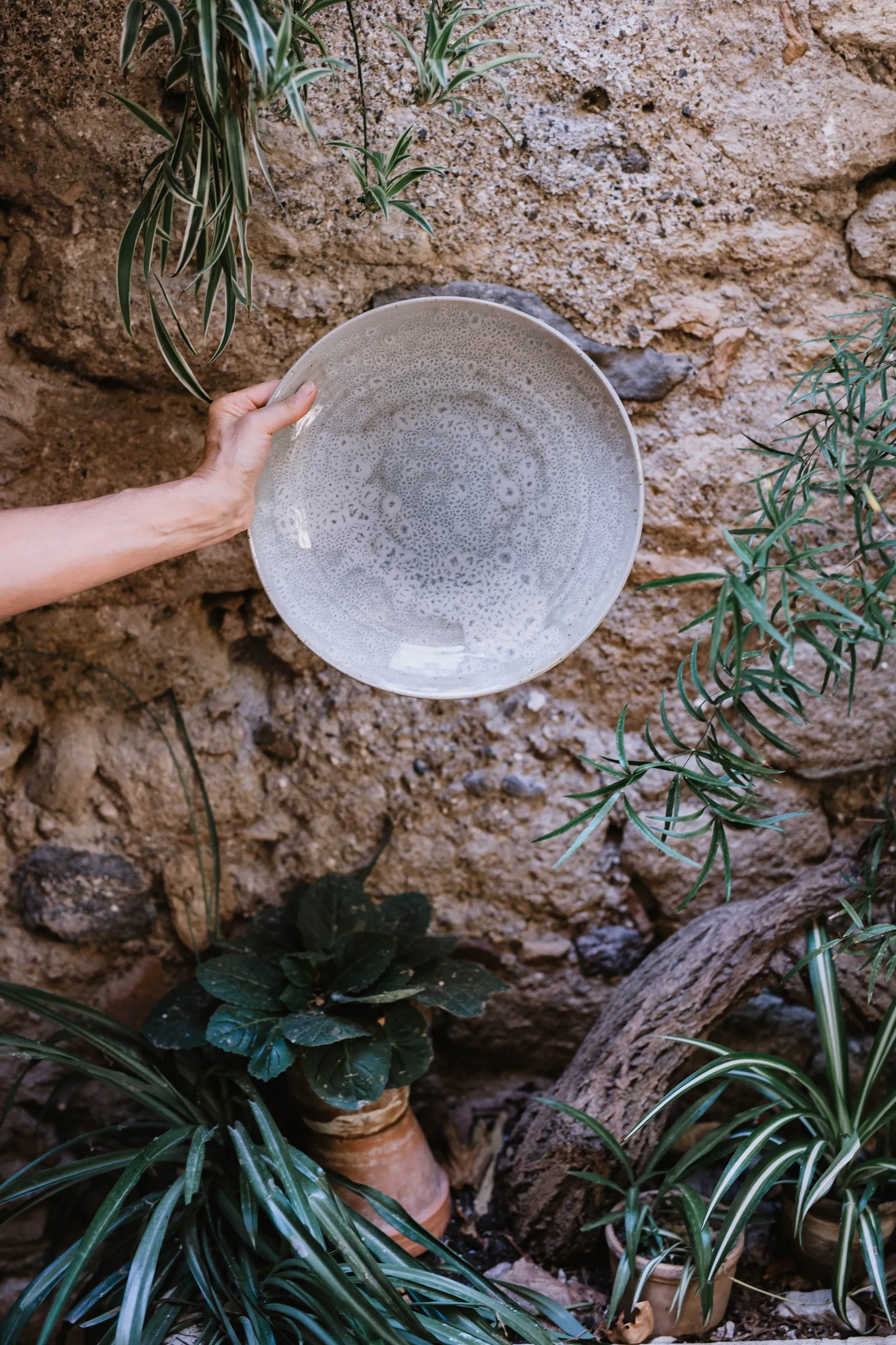 la main de l'artiste présentant une assiette en céramique