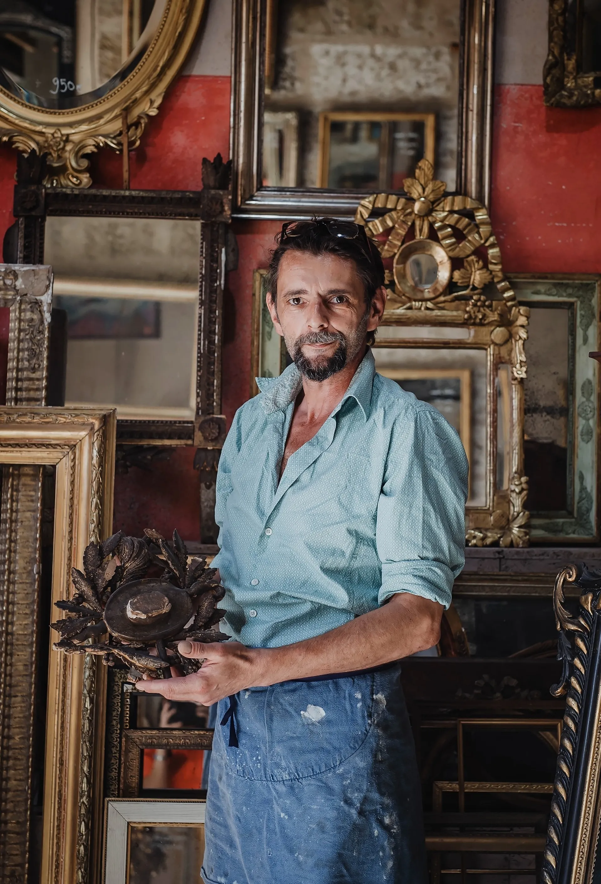 portrait d'Olivier Dahlmann présentant un travail en cours devant ses réalisations de cadres dorés