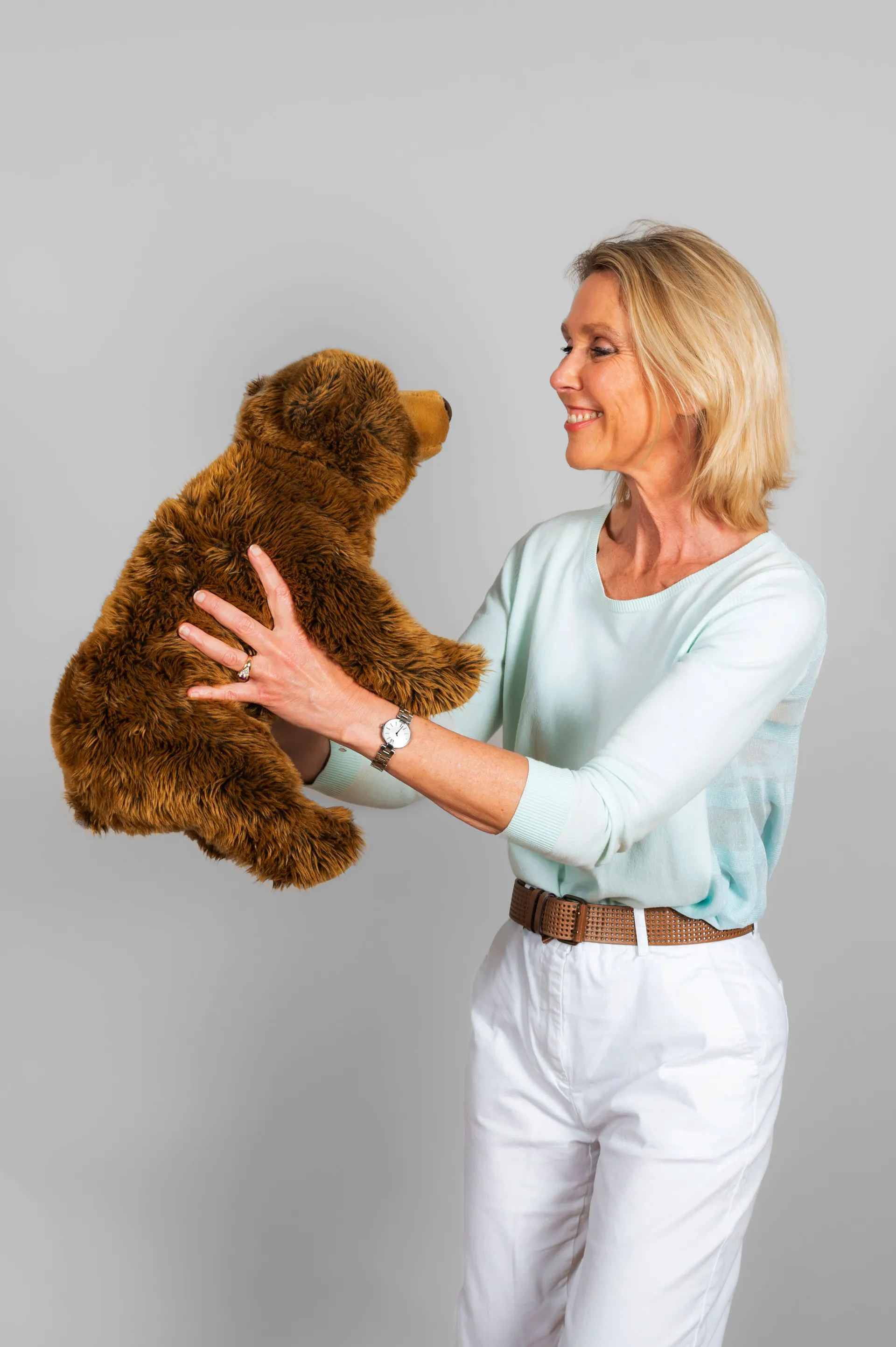 portrait studio d'une femme qui regarde affectuesement un ours en peluche