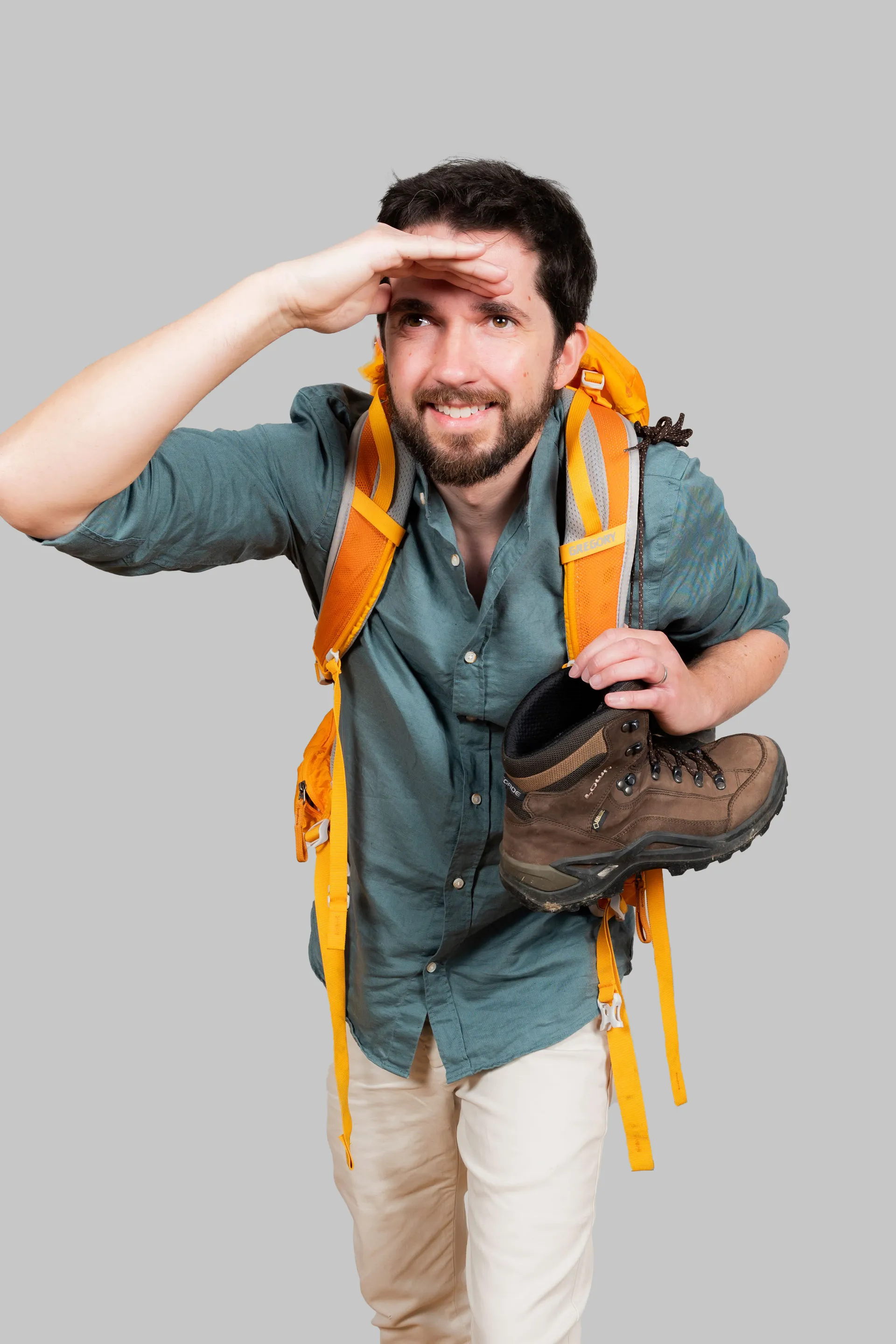 portrait studio d'un homme avec un sac de randonnée sur le dos et une botte à la main