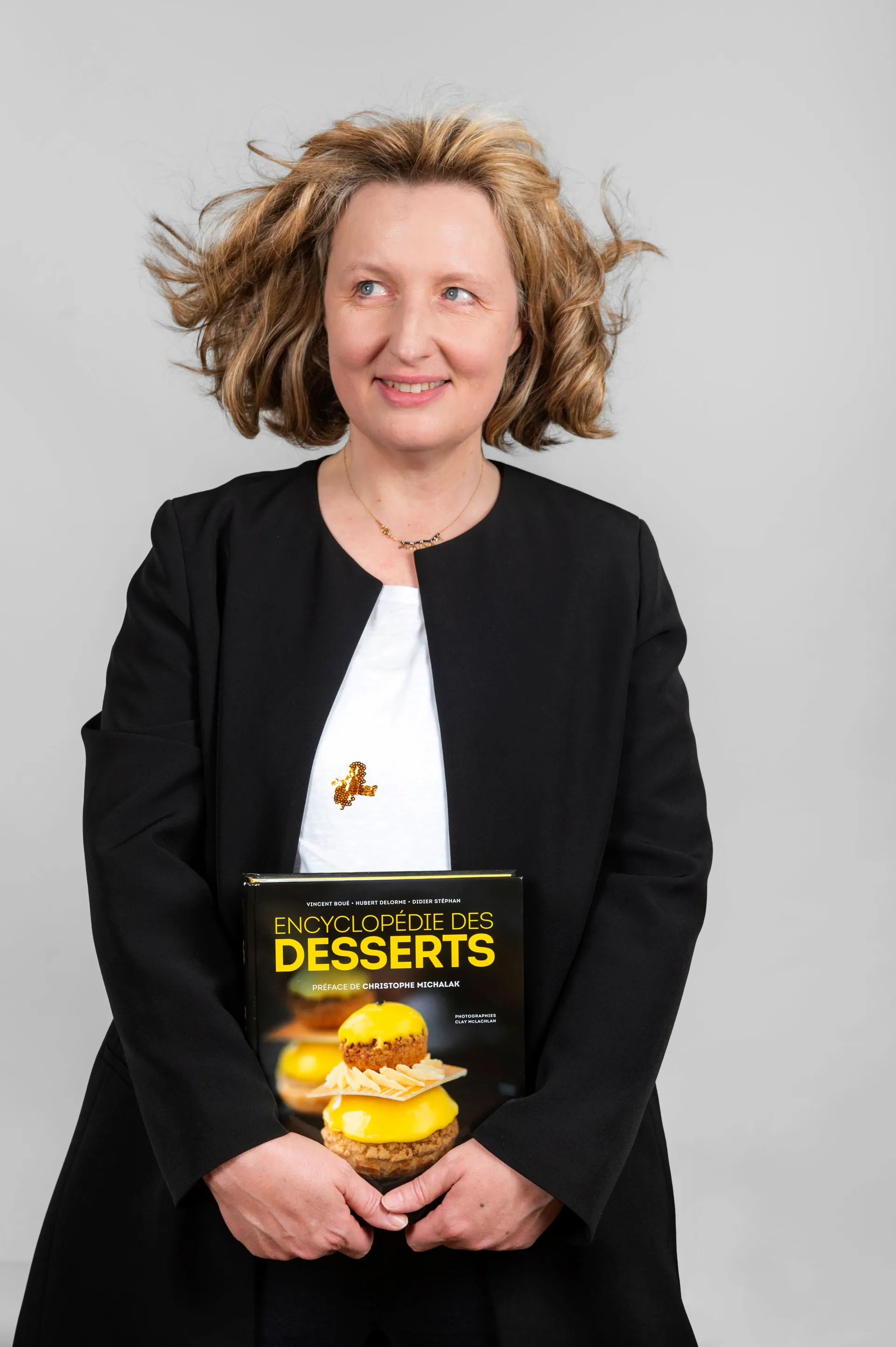 portrait studio d'une femme tenant un livre de recetets de pâtisserie